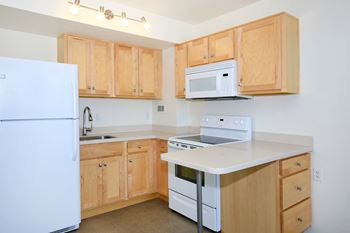 A kitchen with a white refrigerator, white oven, and white microwave
